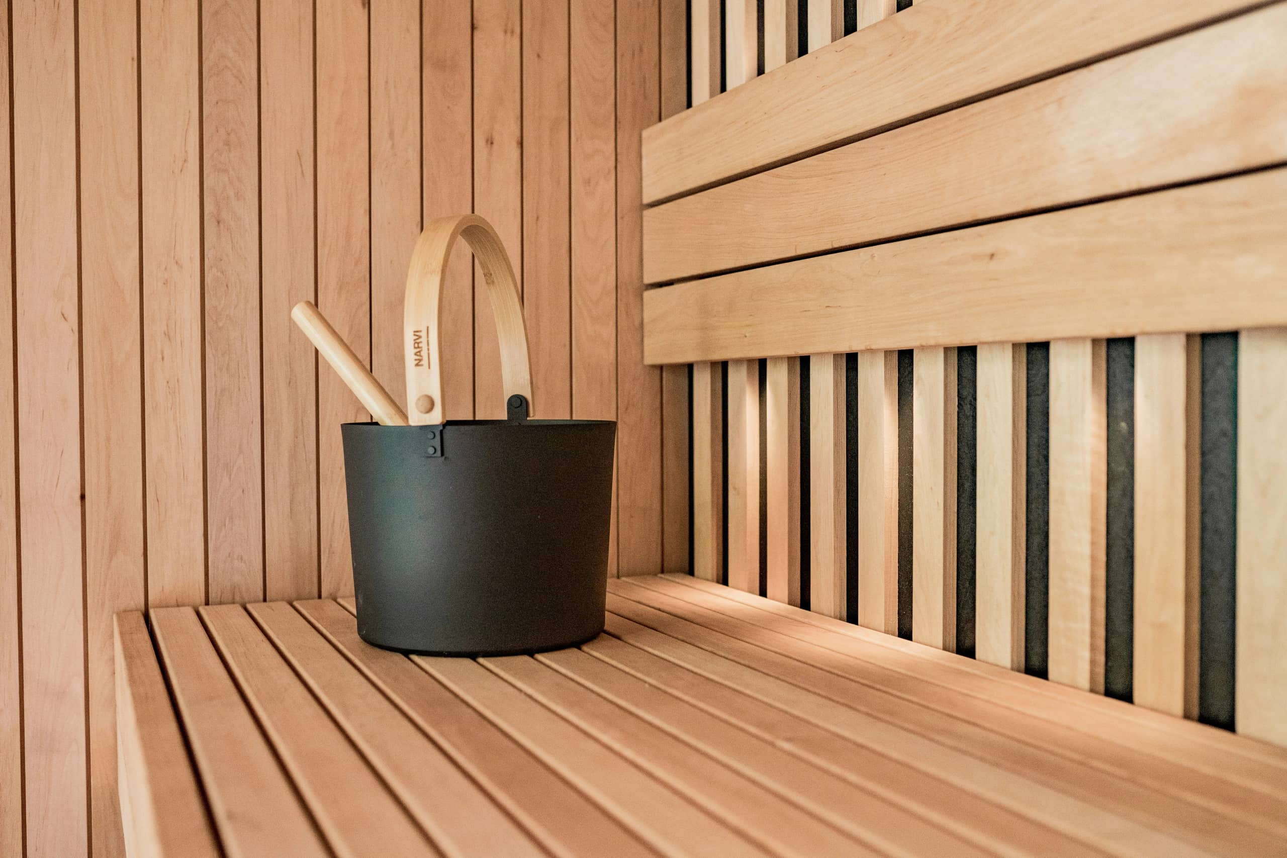 Traditional sauna accessories - water bucket and ladle resting on a wooden bench inside a sauna